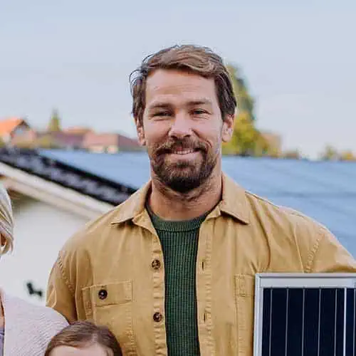 Man holding solar panel outdoors in residential project.